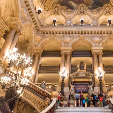 A single visitor crossing the Grand Foyer beneath its chandeliers