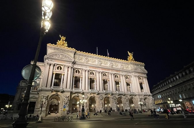 The Paris Opera House lit against a dark sky from the Place de l'Opéra